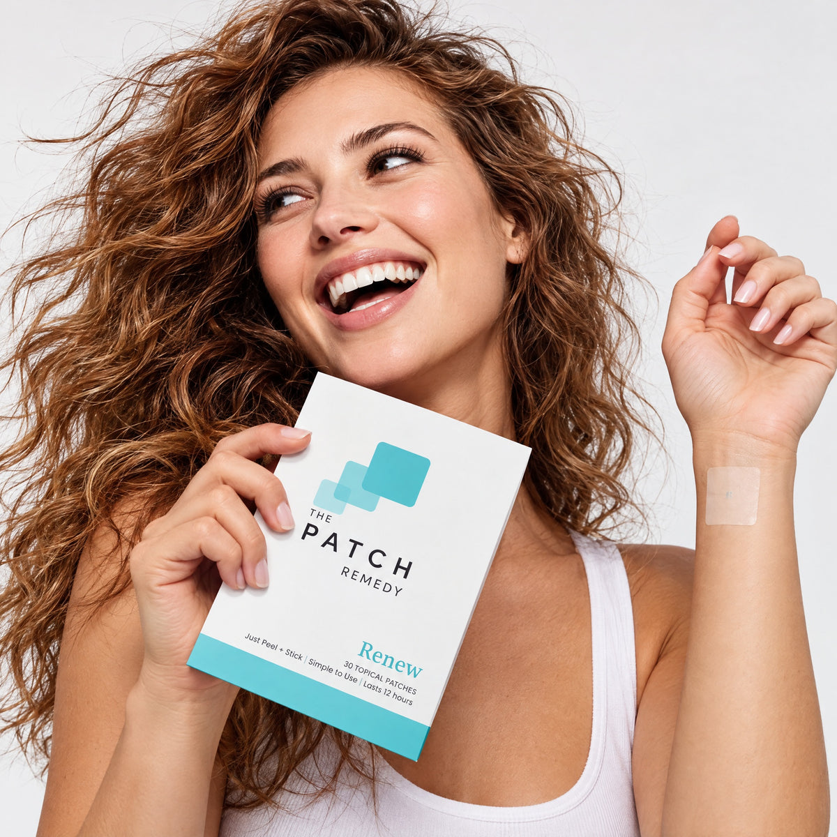 A curly-haired woman holding a Renew pack with a patch on her inner wrist